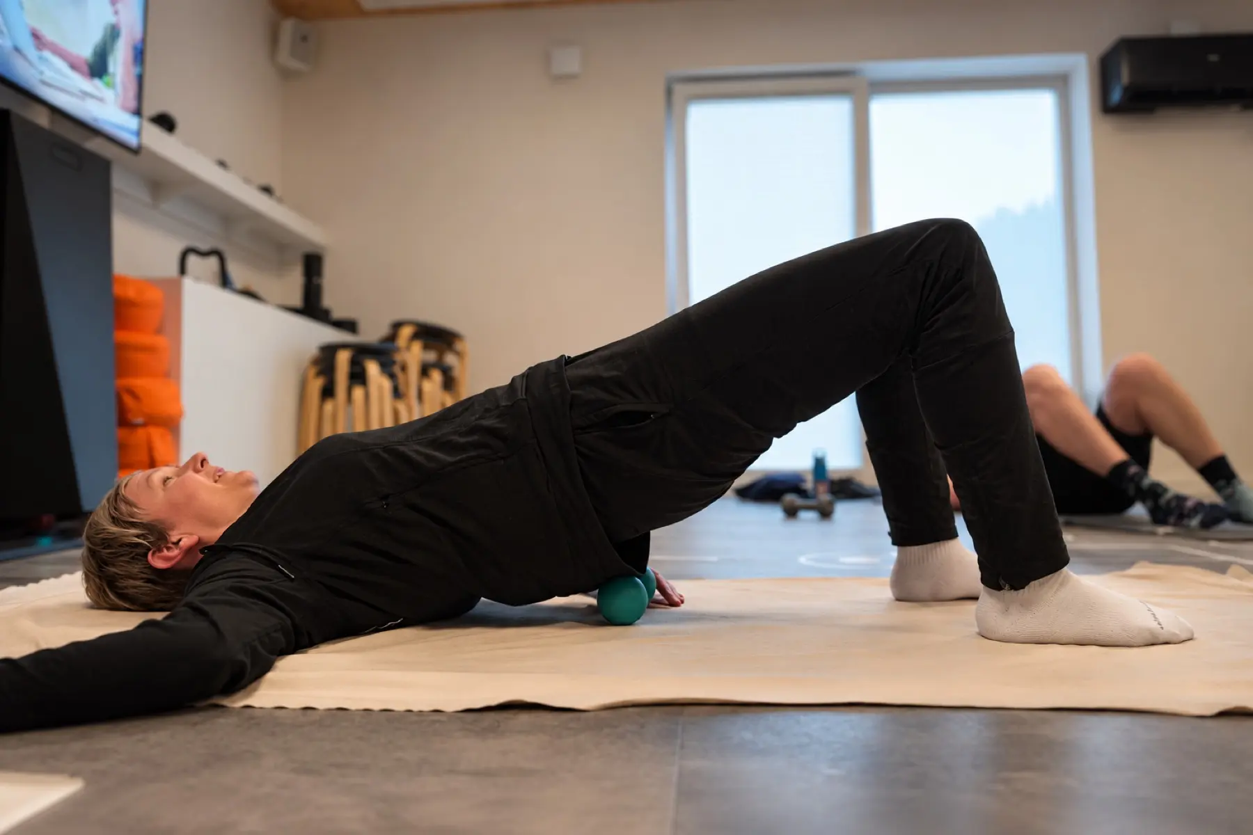 Brückenübung mit Massageball im Therapieraum